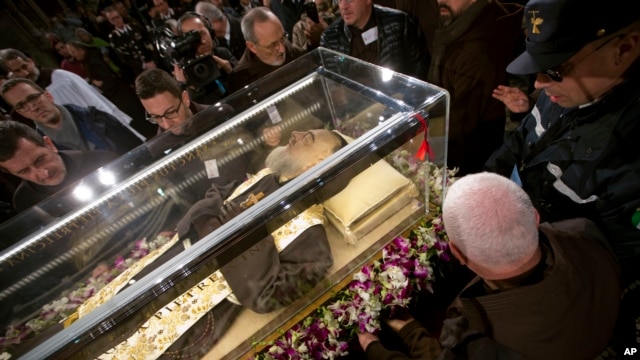 People stand around the mortal remains of Saint Pio (Padre Pio) as they are displayed in Rome's San Lorenzo Basilica, as part of the Roman Catholic Church 2016 Holy Year celebrations, Feb. 3, 2016.