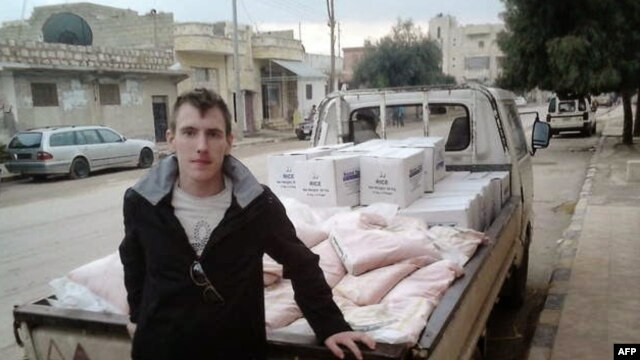 Nhân viên cứu trợ người Mỹ Abdul-Rahman (Peter) Kassig đứng cạnh một xe tải chở hàng cứu trợ.  Anh Kassig bị bắt ở miền đông Syria hồi tháng 10 năm 2013 trong khi phân phát hàng cứu trợ cho một tổ chức từ thiện do anh thành lập.