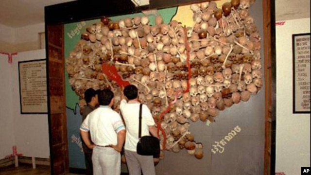 Visitors to Toul Sleng, officially known as S-21 prison look at a wall of sculls and bones made into a map of Cambodia.
