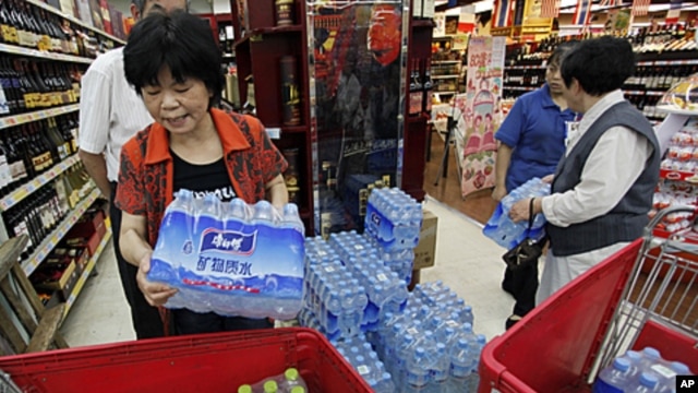 Customers stock cartons of bottled water at a supermarket in Hangzhou, Zhejiang province, after a local river, which is the source of drinking water, was polluted by a chemical leakage, June 6, 2011.