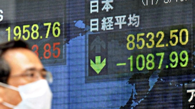 A man walks past a screen displaying stock prices in Tokyo, March 15, 2011
