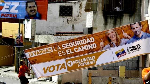 Un correligionario de Henrique Capriles coloca una manta de su candidato, mientras atrás aparece otra de su contincante, el presidente Hugo Chávez.