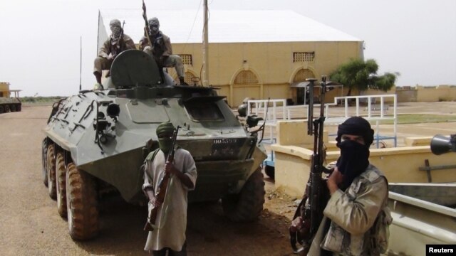 Fighters from the Al Qaeda-linked Islamist group MUJWA, who are traveling with a convoy including Burkina Faso Foreign Minister Djibril Bassole, stand guard in Gao, northern Mali, August 7, 2012. 
