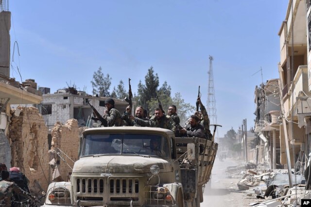 FILE - Syrian soldiers celebrate their victory against the Islamic State group in Qaryatain, Syria, April 4, 2016.