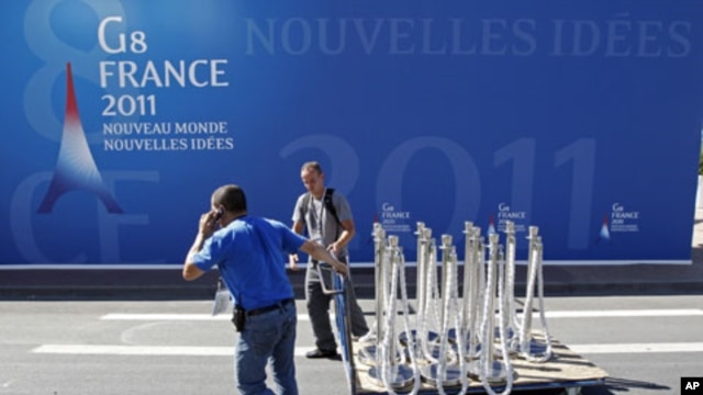 Men work near a G8 backdrop as preparations continue ahead of the G8 summit in Deauville, northern France, May 25, 2011