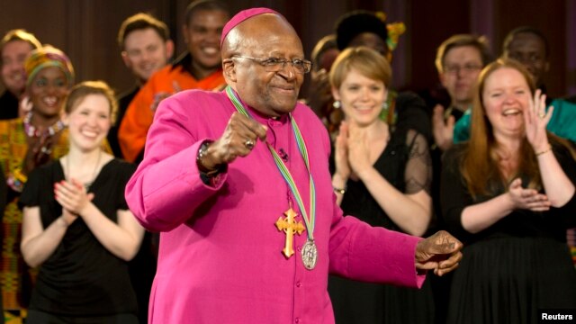 El exobispo anglicano de Cape Town, Desmond Tutu, baila siguiendo el canto de un coro, durante la ceremonia en que recibió el premio Templeton 2013 en Londres. [Foto: Reuters].