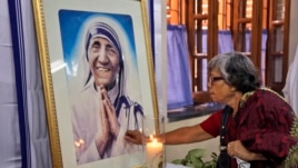 An Indian Catholic woman offers prayers as she touches a portrait of Mother Teresa on her 17th death anniversary at the Missionaries of Charity in Kolkata, India, Sept. 5, 2014.