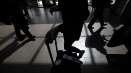 Passengers cast shadows as they walk along a terminal at Los Angeles International Airport in Los Angeles, California, March 4, 2013.