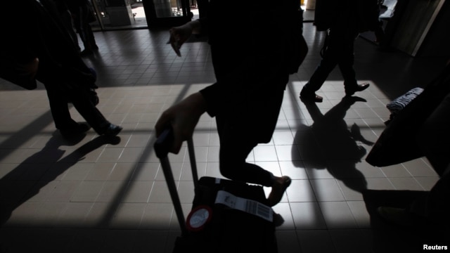 Passengers cast shadows as they walk along a terminal at Los Angeles International Airport in Los Angeles, California, March 4, 2013. 