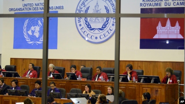 FILE - In this file photo released by the Extraordinary Chambers in the Courts of Cambodia, court officers of the U.N.-backed war crimes tribunal are seen through windows during a hearing of former Khmer Rouge top leaders in Phnom Penh, Cambodia. 