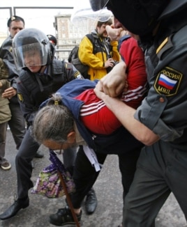 Russian police detain an opposition activist, with the white ribbon as a symbol of protest, during an anti-Kremlin protest in Moscow, May 31, 2012.