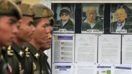 Cambodian military officials line up in front the top leaders of Khmer Rouge portraits, from right,  former Khmer Rouge Foreign Minister Ieng Sary, former Khmer Rouge head of state Khieu Samphan, and  former Deputy Secretary Nuon Chea, during the second day of trial of the U.N.-backed war crimes tribunal in Phnom Penh, Cambodia, Tuesday, Dec. 6, 2011. Three senior leaders of Cambodia's brutal Khmer Rouge regime on Tuesday continue to be questioned at the U.N.-backed tribunal over their roles in the deaths of an estimated 1.7 million people when their movement held power in the 1970s.
