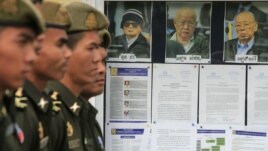 Cambodian military officials line up in front the top leaders of Khmer Rouge portraits, from right,  former Khmer Rouge Foreign Minister Ieng Sary, former Khmer Rouge head of state Khieu Samphan, and  former Deputy Secretary Nuon Chea, during the second day of trial of the U.N.-backed war crimes tribunal in Phnom Penh, Cambodia, Tuesday, Dec. 6, 2011. Three senior leaders of Cambodia's brutal Khmer Rouge regime on Tuesday continue to be questioned at the U.N.-backed tribunal over their roles in the deaths of an estimated 1.7 million people when their movement held power in the 1970s. (AP Photo/Heng Sinith)