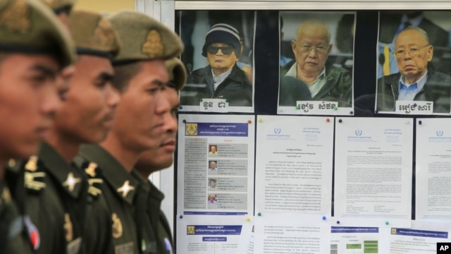 Cambodian military officials line up in front the top leaders of Khmer Rouge portraits, from right,  former Khmer Rouge Foreign Minister Ieng Sary, former Khmer Rouge head of state Khieu Samphan, and  former Deputy Secretary Nuon Chea, during the second day of trial of the U.N.-backed war crimes tribunal in Phnom Penh, Cambodia, Tuesday, Dec. 6, 2011. Three senior leaders of Cambodia's brutal Khmer Rouge regime on Tuesday continue to be questioned at the U.N.-backed tribunal over their roles in the deaths of an estimated 1.7 million people when their movement held power in the 1970s.