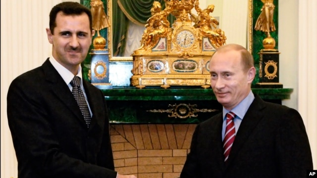 FILE -  In this Dec. 19, 2006 file photo Vladimir Putin, then Russian President, right, and his Syrian counterpart Bashar Assad smile as they shake hands in Moscow's Kremlin. 