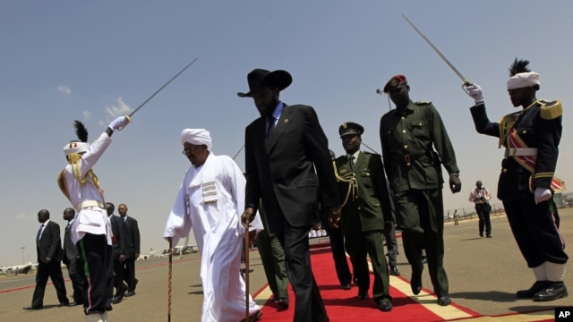 South Sudanese President Salva Kiir (C) walks with his Sudanese counterpart Omar al-Bashir (in white) before Kiir's departure from Khartoum, October 9, 2011. 