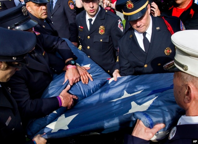 FILE - The National 9/11 Flag is folded by firefighters after a ceremony at the 9/11 Memorial in New York, May 21, 2014.