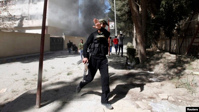 A fighter from the Islamist Syrian rebel group Jabhat al-Nusra reacts to his picture being taken as their base is shelled in Raqqa province, eastern Syria, Mar.14, 2013. 