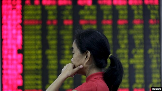 An investor looks at an electronic board showing stock information at a brokerage house in Beijing, Aug. 26, 2015.