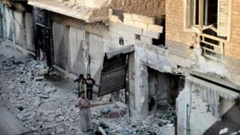 In this citizen journalism image taken on Saturday, July 28, 2012 and provided by Edlib News Network ENN, a Syrian family stand in the rubble of destroyed houses in Maarat al-Numaan on the eastern edge of Idlib province, northern Syria. 