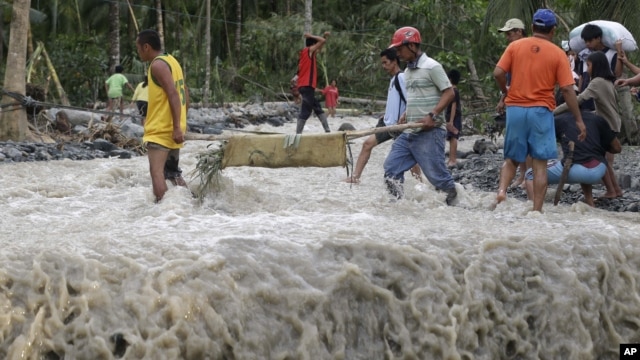 Residents cross a river with the body of a child after retrieving it from the flash flood-hit village of Andap, in New Bataan township, Compostela Valley in southern Philippines, December 5, 2012.