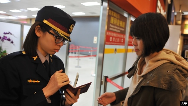 Nhân viên an ninh sân bay kiểm tra hộ chiếu và thẻ lên máy bay của một hành khách tại phi trường Taipei Songshan, ngày 10/3/2014.