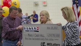 Mark (L) and Cindy (C) Hill are presented a check by a Missouri Lottery official during the announcement of Powerball winners in Dearborn, Missouri, November 30, 2012.