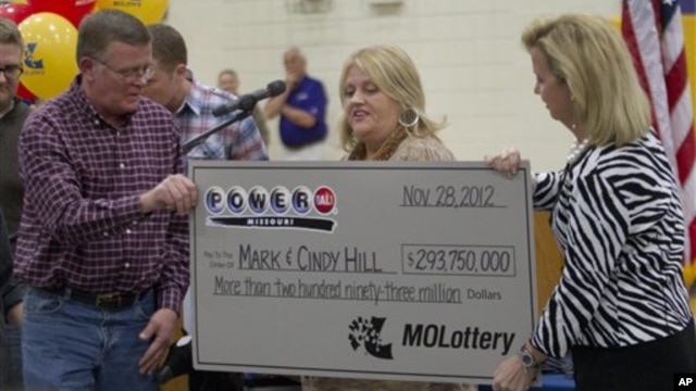Mark (L) and Cindy (C) Hill are presented a check by a Missouri Lottery official during the announcement of Powerball winners in Dearborn, Missouri, November 30, 2012.