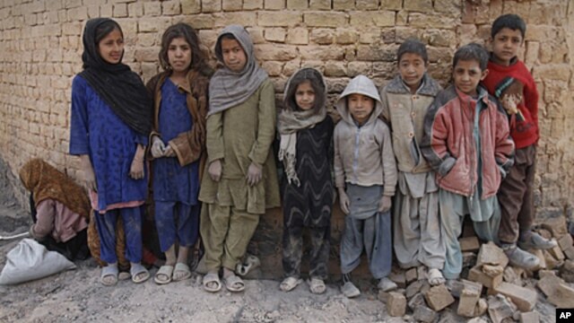 Afghan children pose for the camera, pausing during their work to sift the usable residue from the ashes of coal used at a brick factory during the cold days of a harsh winter in Kabul, Afghanistan. Thousands of Afghan children work to make money to suppo