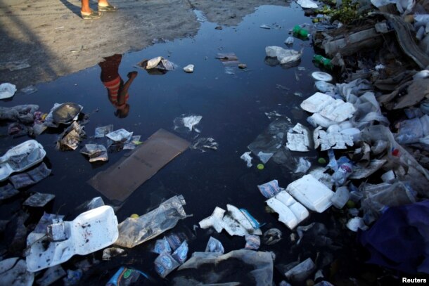 A woman is reflected in a puddle on a street in Port-au-Prince, Haiti, Aug. 17, 2016.