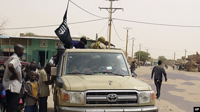 Fighters from the Ansar Dine group, flying the group's black flag, instruct local residents in how to follow Shariah, as they stop in a market area of Timbuktu, Mali, April 14, 2012. 