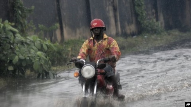 A man ride on motor cycle through a flooded street following a heavy downpour in Lagos, Nigeria, July 11, 2011