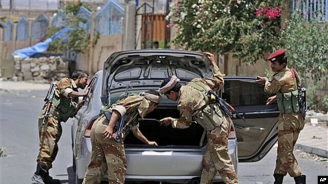 Yemeni army soldiers check a car in Sana'a, Yemen, as government troops try to recapture areas held by Islamic militants, June 9, 2011