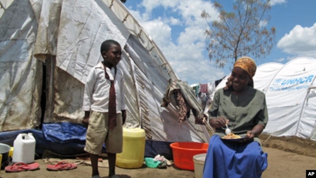 A boy talks to his mother, both internally-displaced persons, as she has lunch outside their temporary holding ground in Nakuru, Kenya, April 2008 (file photo)