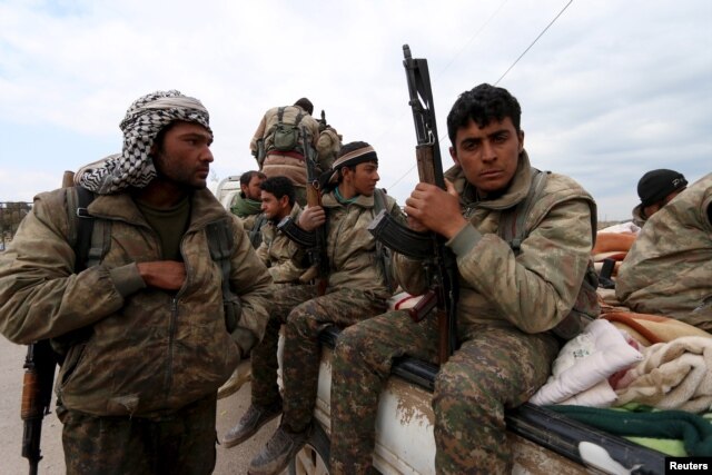 Kurdish People's Protection Units (YPG) fighters carry their weapons while riding on the back of a pick-up truck in Qamishli, Syria, March 11, 2016.
