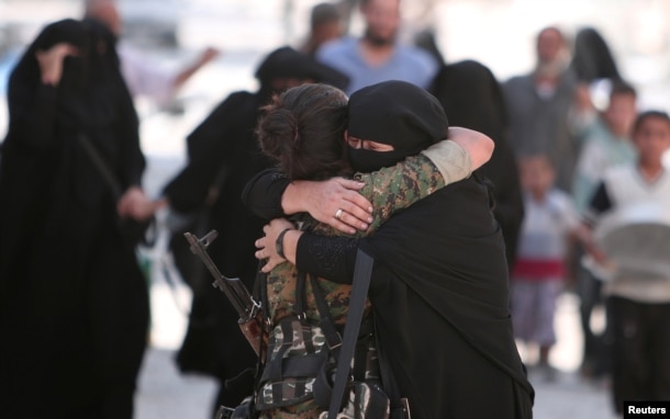FILE - A woman embraces a Syria Democratic Forces (SDF) fighter after she was evacuated with others by the SDF from an Islamic State-controlled neighborhood of Manbij, in Aleppo Governorate, Syria, Aug. 12, 2016.