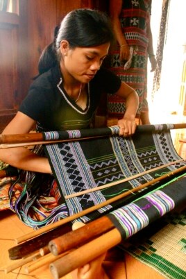 Một người phụ nữ A Lưới đang dệt một tấm vải thổ cẩm