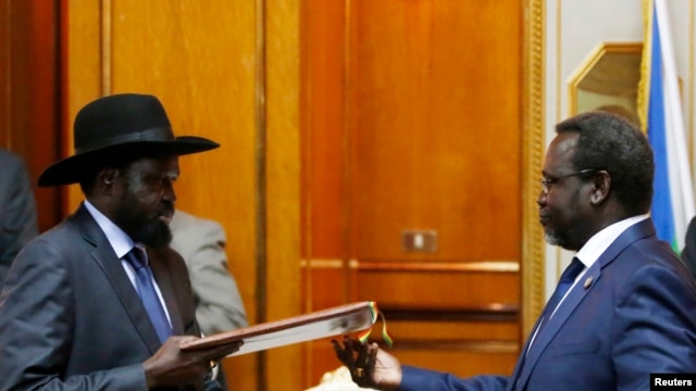 South Sudan's rebel leader Riek Machar (R) and South Sudan's President Salva Kiir (L) exchange signed peace agreement documents in Addis Ababa, Ethiopia, May 9, 2014.