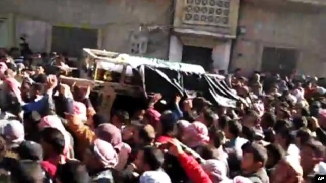 In this image from TV shown on the internet made available by the Sham News Network, protesters carry the body of Tamer Mutlaq in Homs, Syria, December 20, 2011.