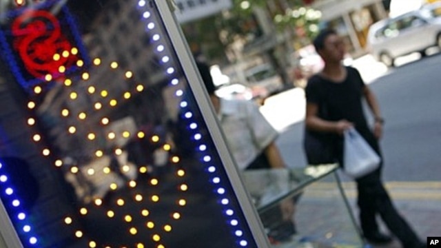 Pedestrians walk past a money exchange outlet in Hong Kong on August 6, 2011