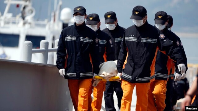 Para petugas penyelamat menggotong jenazah para penmupang kapal Sewol yang tenggelam di pelabuhan Jindo (20/4). (Reuters/Kim Hong-Ji)