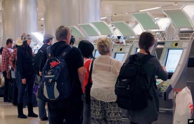 FILE - Passengers arriving from abroad at Los Angeles International Airport use new automated passport kiosks.