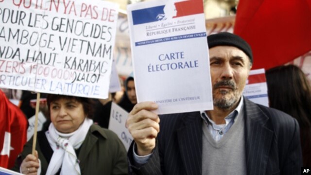 Turkish citizens in France, one of them holding a booklet reading "Electoral card", demonstrate in front of the Senate to protest against a law that would make it a crime to deny "genocide" of Armenians, in Paris, Monday, Jan. 23, 2012.