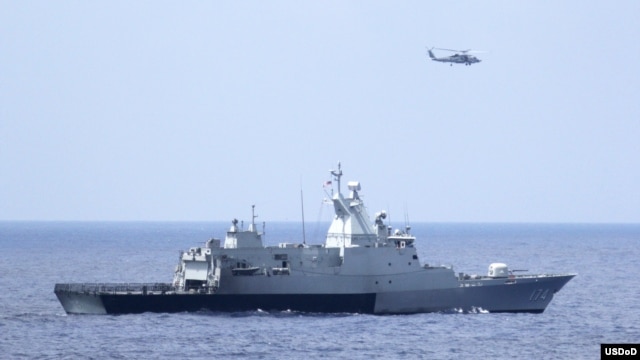 The Royal Malaysian Navy corvette KD Terengganu and a U.S. Navy MH-60R Sea Hawk helicopter conduct a coordinated air and sea search for a missing Malaysian Airlines jet in the Gulf of Thailand, March 12, 2014. (U.S. Navy photo by Operations Specialist 1st Class Claudia Franco)