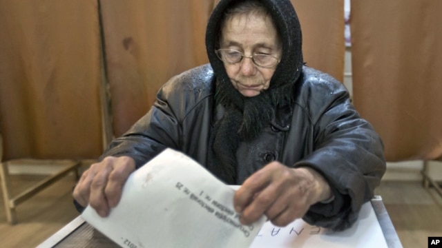 An elderly woman casts a ballot in Sintesti, Romania, Sunday, December 9, 2012. 