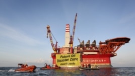 This handout photo taken by Greenpeace on August 25, 2012 shows Greenpeace activists holding a banner in front of the Gazprom 'Prirazlomnaya' oil drilling platform during their protest in the Barents Sea as the Gazprom support boat secures the area.