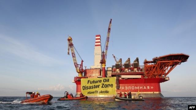 This handout photo taken by Greenpeace on August 25, 2012 shows Greenpeace activists holding a banner in front of the Gazprom 'Prirazlomnaya' oil drilling platform during their protest in the Barents Sea as the Gazprom support boat secures the area.