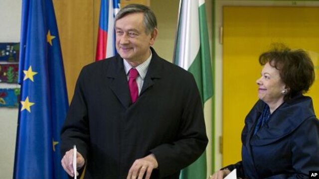 Slovenia's president Danilo Turk, left, casts his ballot as his wife Barbara Miklic, right, looks on at a polling station in Ljubljana, December 4, 2011.