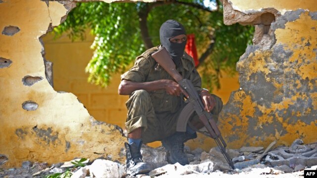FILE - A Somali soldier stands guard next to the site where al-Shabab militants carried out a suicide attack against a military intelligence base in Mogadishu, June 2015.