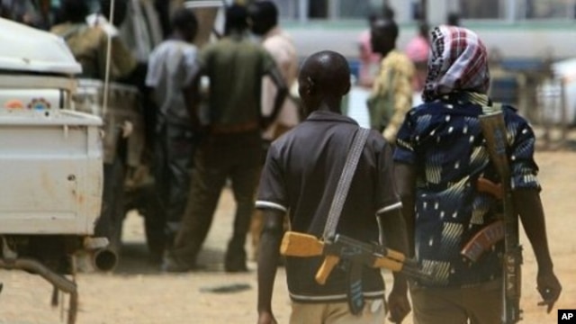 Armed men walk past on April 17, 2011 as resentment towards the capital Khartoum runs high in the restive town of Abyei, on the Sudanese north-south border.